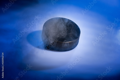 Closeup of a rubbery ice hockey puck against a blue smoky background. photo