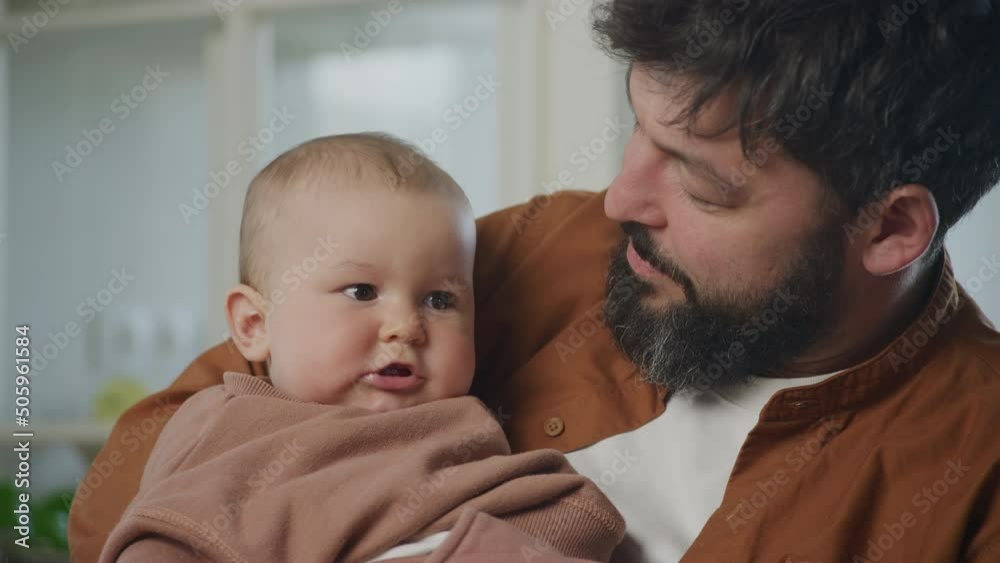 Close up portrait of a young father cuddle with his baby son indoors Close up portrait of a young father cuddle with his baby son indoors