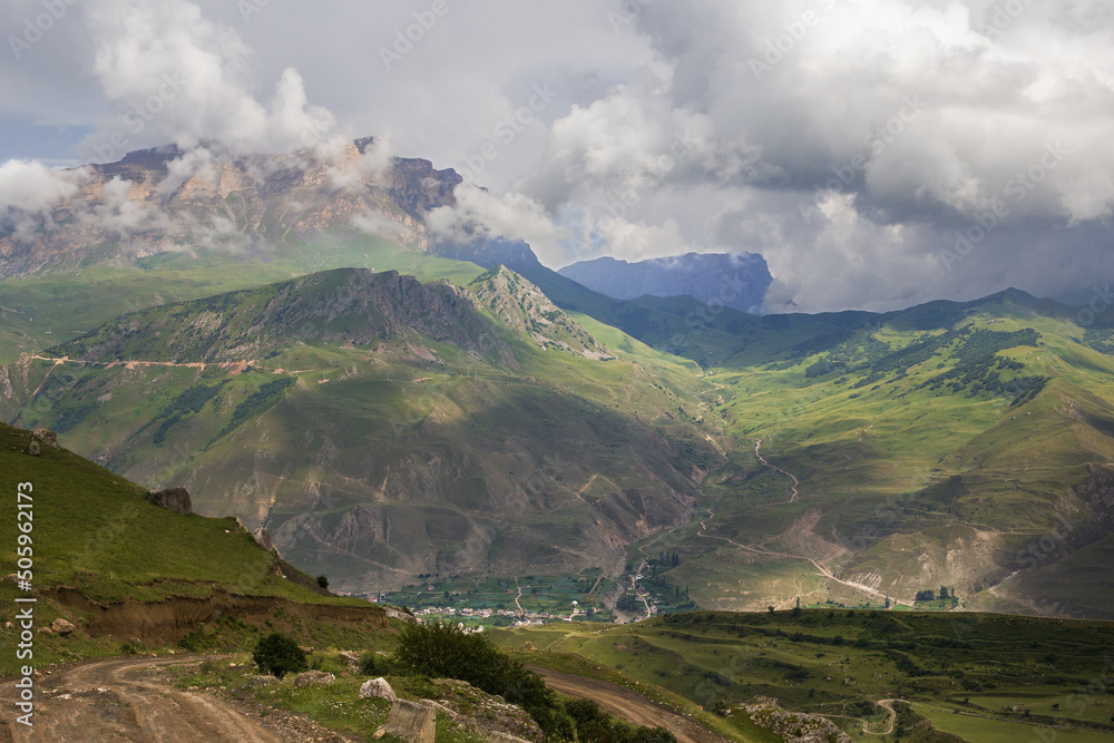 Top view of the mountain valley and the mountain village. Clouds and cumulus clouds over the mountains. Soft focus.