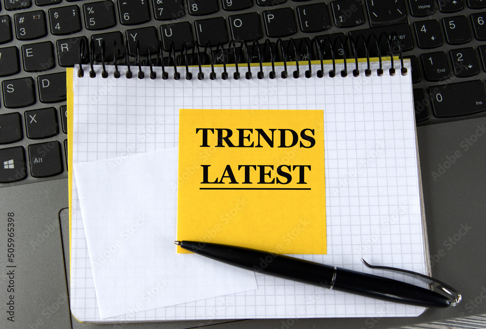 Φωτογραφία TRENDS LATEST - words on a yellow piece of paper on the background of a laptop w