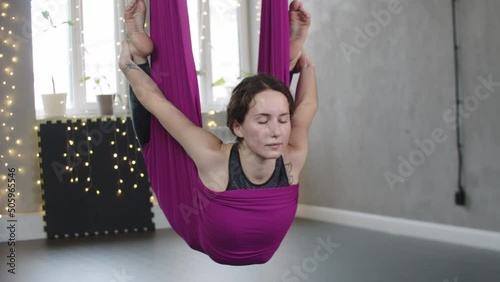 Young woman hanging on the yoga hammock and holding her ankles photo