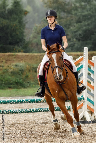 Young horse rider girl on show jumping course in equestrian sports competition. Vertical photo