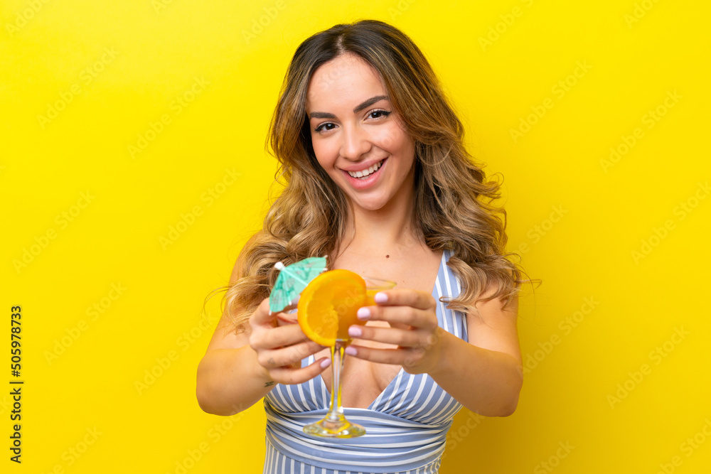 Young caucasian woman isolated on yellow background in swimsuit and holding a cocktail Young caucasian woman isolated on yellow background in swimsuit and holding a cocktail