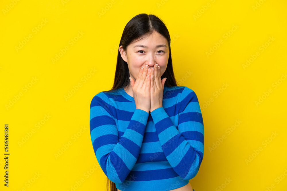 Young Chinese woman isolated on yellow background happy and smiling covering mouth with hands Young Chinese woman isolated on yellow background happy and smiling covering mouth with hands