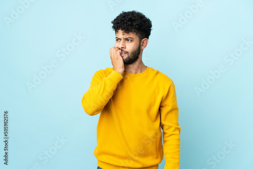 Young Moroccan man isolated on blue background is a little bit nervous