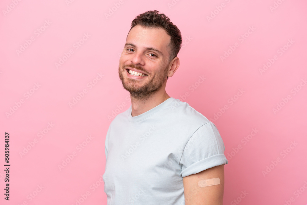 Young Brazilian man wearing a band-aids isolated on pink background smiling a lot Young Brazilian man wearing a band-aids isolated on pink background smiling a lot