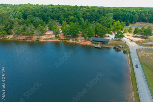 a gorgeous green rippling lake surrounded by lush green trees, grass and plants with blue sky and clouds and buildings among the trees at Lake Spivey Recreation Center in Jonesboro Georgia USA photo