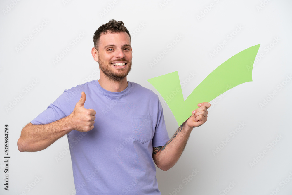 Young Brazilian man isolated on white background holding a check icon with thumb up Young Brazilian man isolated on white background holding a check icon with thumb up