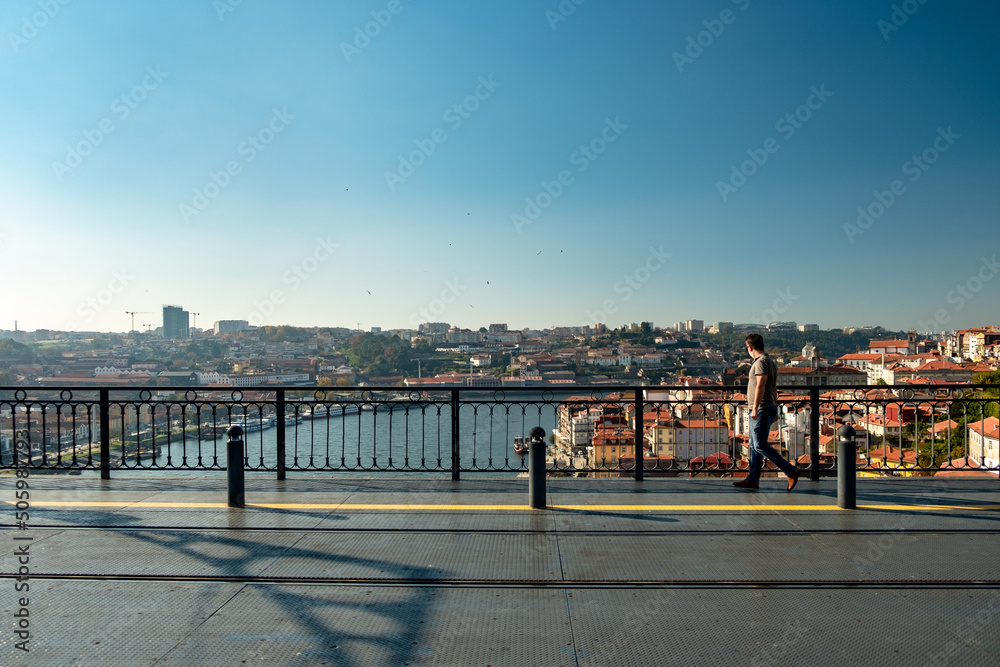 Panoramic view over the metro deck on the bridge of - D. Luís I - with one men looking from the side to the Douro River in the Background. City of Oporto in Portugal.
