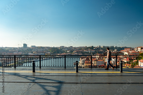 Panoramic view over the metro deck on the bridge of - D. Luís I - with one men looking from the side to the Douro River in the Background. City of Oporto in Portugal. © Vitor Miranda