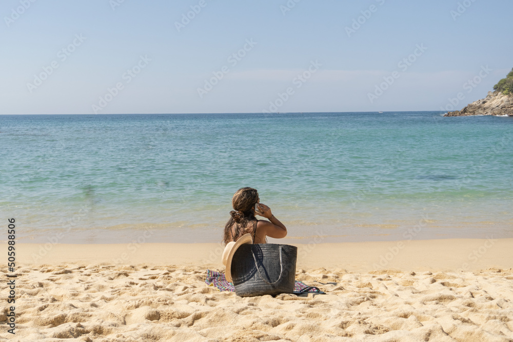Mujer en la playa hablando por teléfono.  
Woman on the beach talking on the phone.