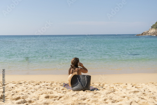 Mujer en la playa hablando por teléfono. Woman on the beach talking on the phone.