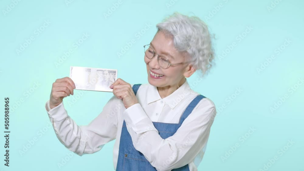 お金を持って喜ぶシニア女性 お金を持って喜ぶシニア女性
