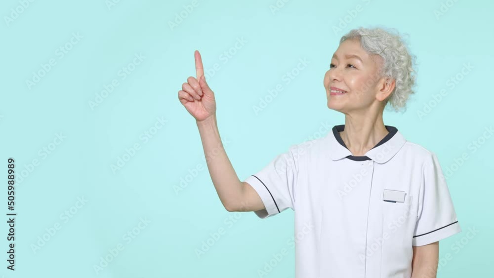 笑顔で指をさす白衣のシニア女性 笑顔で指をさす白衣のシニア女性