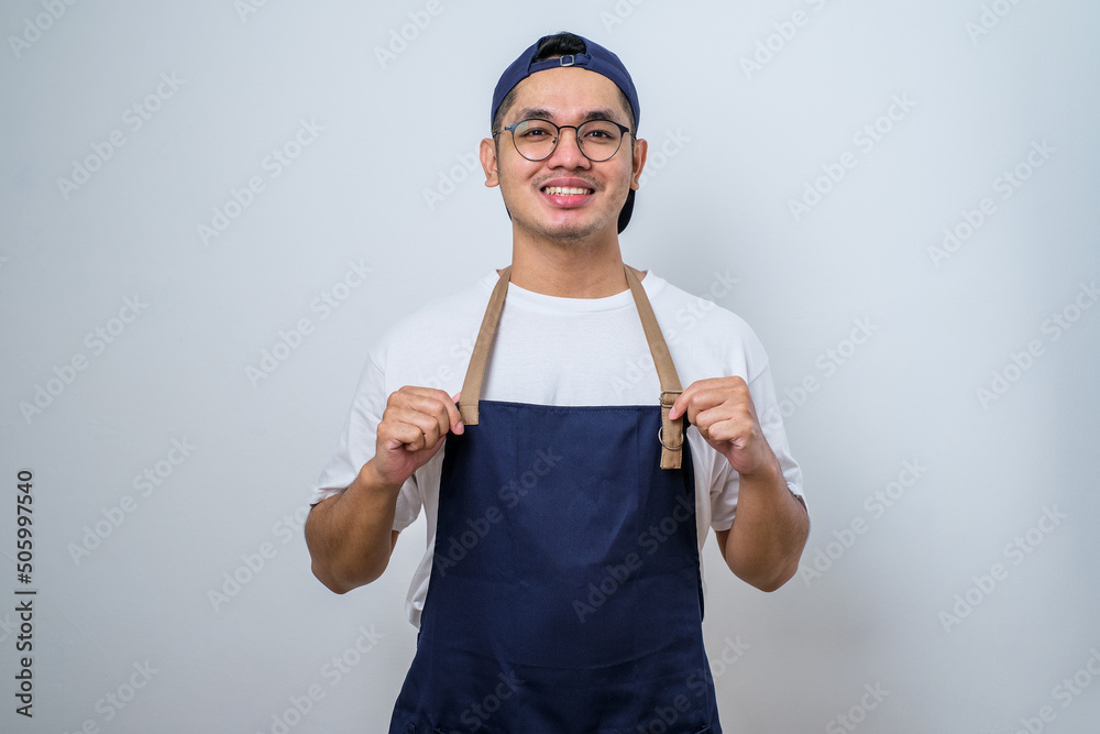 Naklejka premium Young barista man wearing apron standing proudly wearing apron