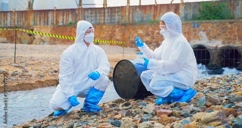 Team of Scientists in protective suits or Biologist collect sample of dirty water smelly and toxic water from factory took a sample of waste water for analysis. Pollution and environment problems