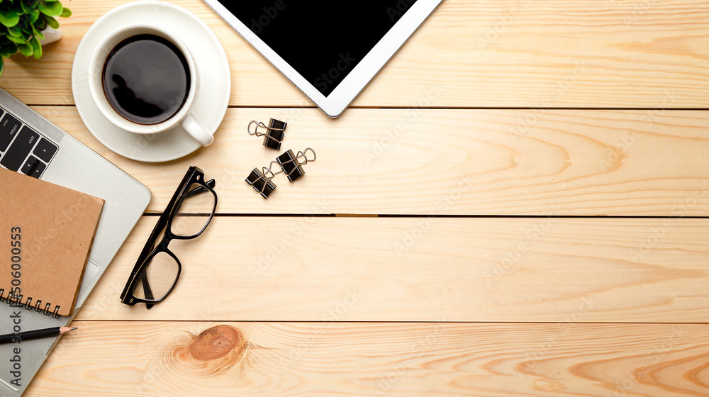 Top view office table desk. Workspace with blank, office supplies,Laptop, pencil, green leaf, and coffee cup on wood background. Top view office table desk. Workspace with blank, office supplies,Laptop, pencil, green leaf, and coffee cup on wood background.