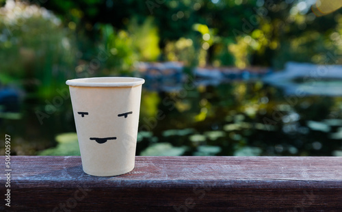 Eco brown paper coffee cups on wooden table with blurred afternoon sunlight background. Environmentally friendly Concept.