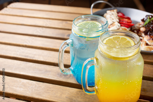 A view of two brightly colored refreshing beverages inside mason jars, on the right side of the frame.