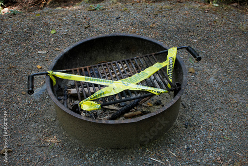 A view of yellow caution tape covering a campground fire pit during a provisional fire use ban. photo