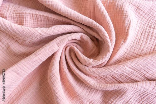 Soft muslin baby blanket background. Cotton clothing and textiles. Natural organic fabrics texture. Light pink rose color. Close up.