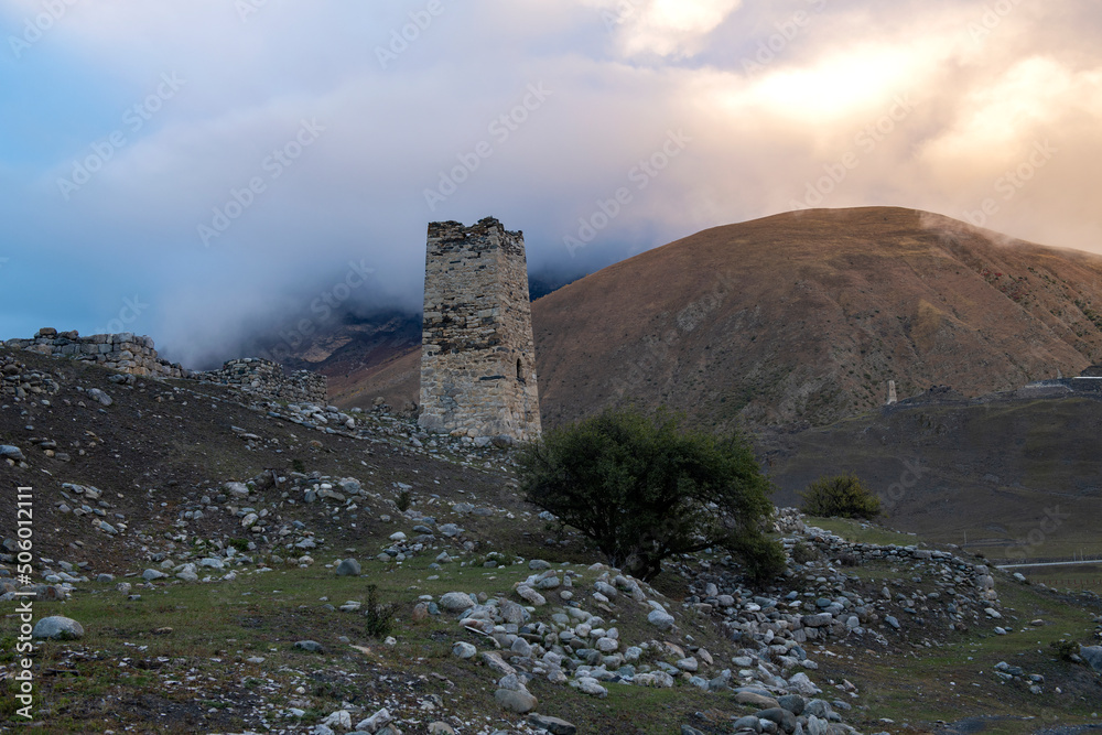 Ancient Ossetian battle tower against a foggy sunset. Verhniy Fiagdon. Northern Ossetia, Russia
