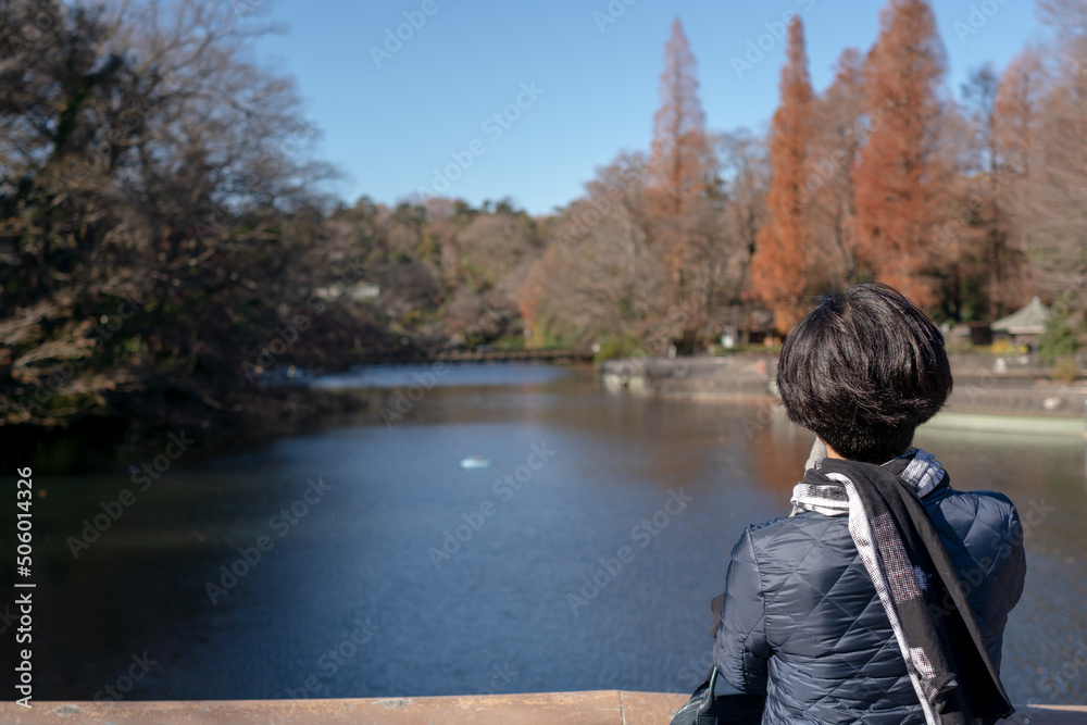 Fototapeta premium Photo from behind of woman relaxing in beautiful nature view at Inokashira Park, Kichijoji, Tokyo