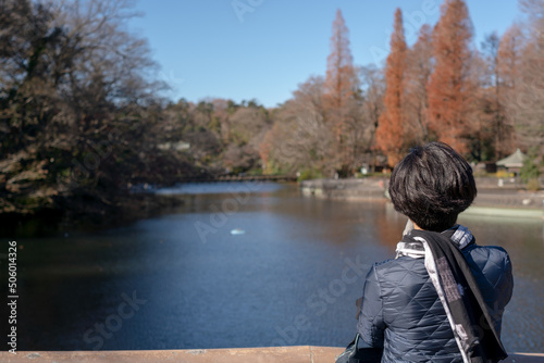 Photo from behind of woman relaxing in beautiful nature view at Inokashira Park, Kichijoji, Tokyo