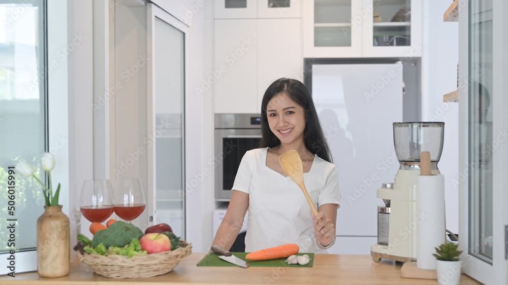 Cheerful asian standing at modern kitchen counter and preparing ingredient for making vegetarian food