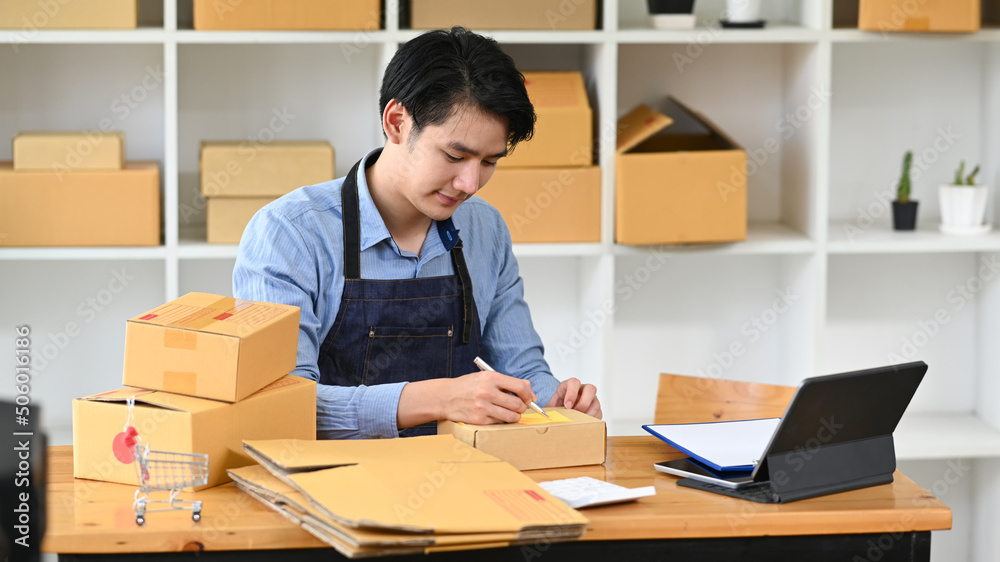 Young man online seller prepare parcel box of product for deliver to customer. Concept of online selling, e-commerce Young man online seller prepare parcel box of product for deliver to customer. Concept of online selling, e-commerce