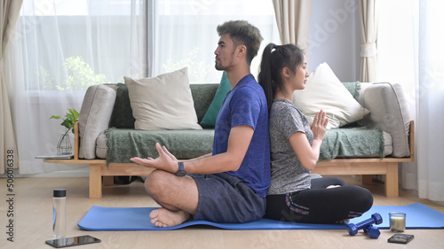 Healthy young couple meditating, sitting in lotus position on mat. Healthy lifestyle, yoga, pilates, exercising concept