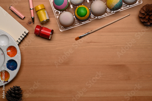 Top view Easter eggs  palette and paintbrush on wooden background with copy space.