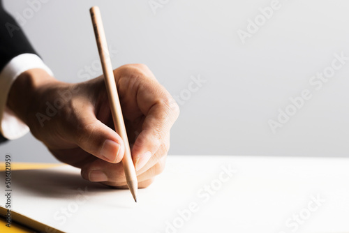 Businessman’s hand holding a wooden pencil.