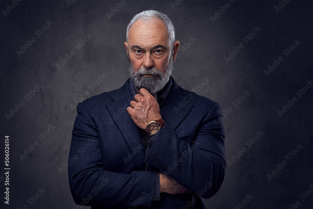Portrait of thoughtful senior man dressed in stylish jacket and shirt against dark background. Portrait of thoughtful senior man dressed in stylish jacket and shirt against dark background.