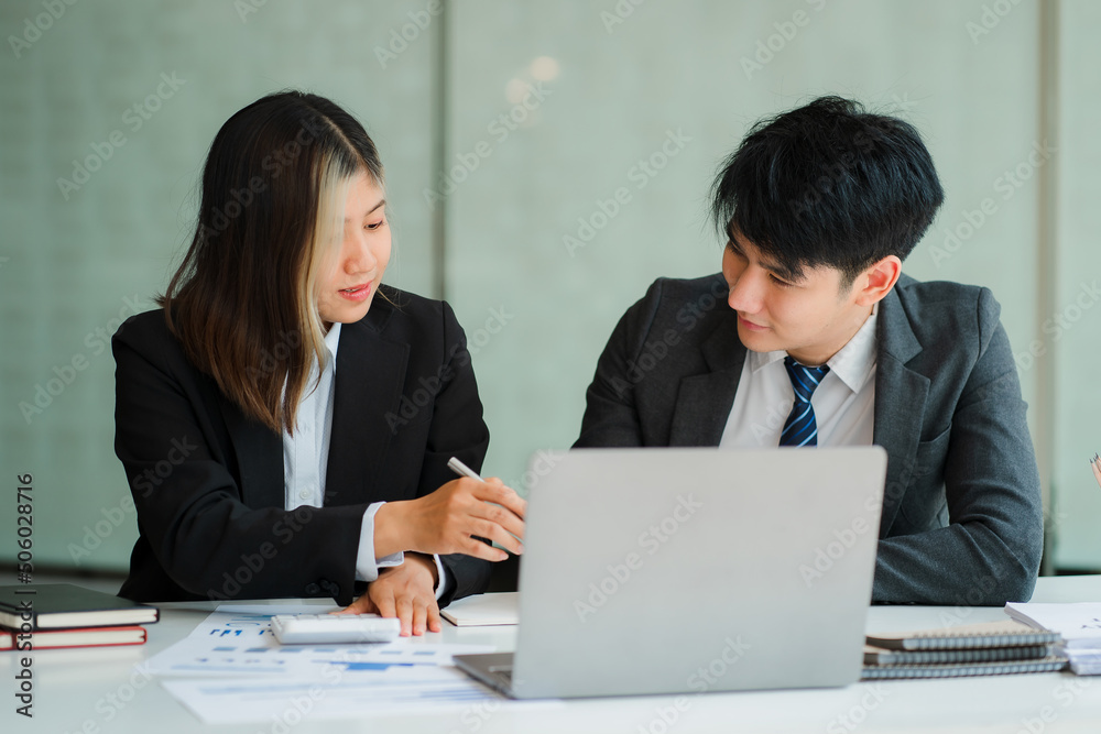 Two young Asian businessmen and women working together meet at the Financial Graphing Computing Office. Share ideas, discuss and train business plans on a laptop. Two young Asian businessmen and women working together meet at the Financial Graphing Computing Office. Share ideas, discuss and train business plans on a laptop.