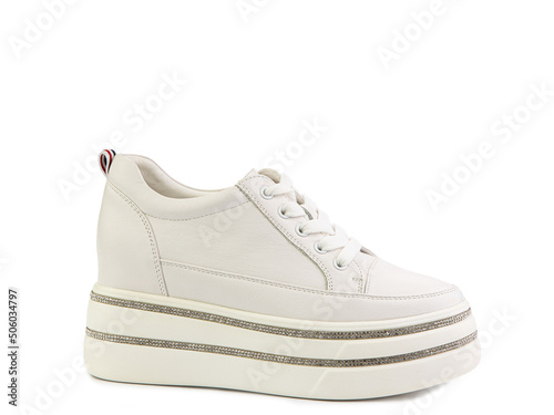 White classic leather trainers. Casual women's style. White lacing and white rubber soles. Isolated close-up on white background.