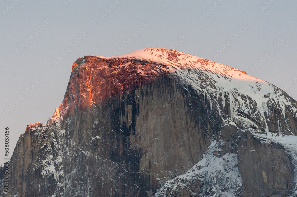 The last light of the setting sun illuminating a snow-covered half-dome on a winter afternoon. Yosemite national park.