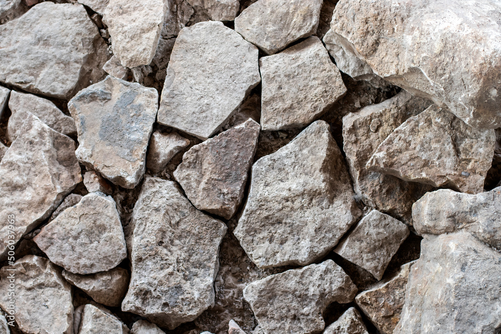 Fragment of a wall of roughly processed gray granite stones. Weathered Stonewall Background from a Castle Wall.