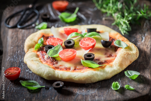 Homemade pizza with cheese, olives and herbs.