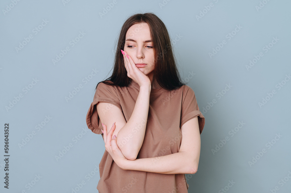 A portrait of a girl holds her palm near her cheek, showing with facial expressions that her tooth hurts A portrait of a girl holds her palm near her cheek, showing with facial expressions that her tooth hurts