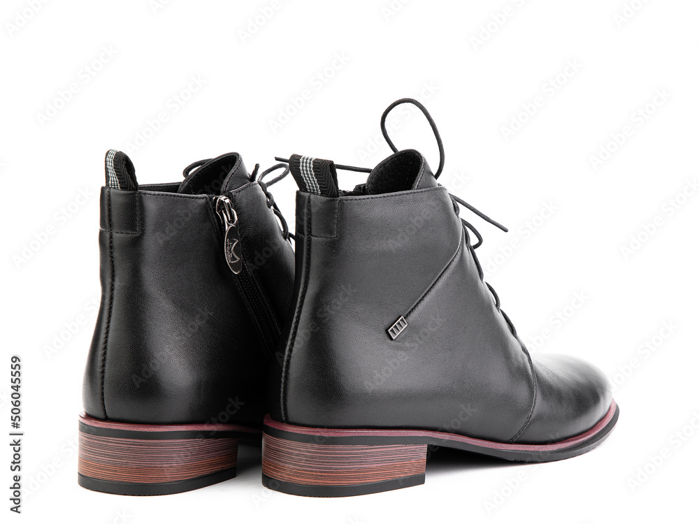 Women's autumn ankle black leather boots with black zip and average brown heels, isolated white background. Back side view. Fashion shoes.