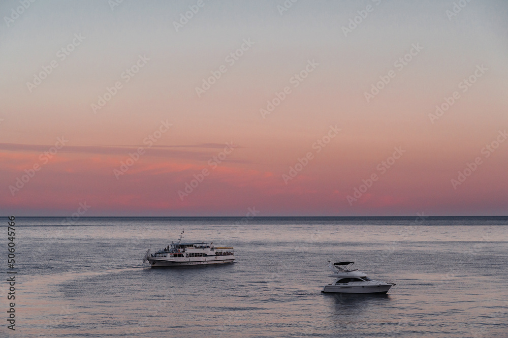 white motor yacht and cruise liner at sea on summer evening at sunset