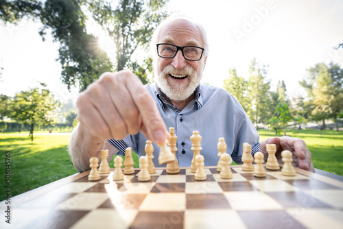 Group of senior friends playing chess at the park