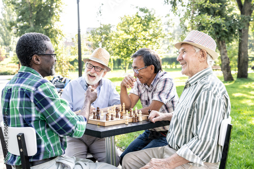 Group of senior friends playing chess at the park