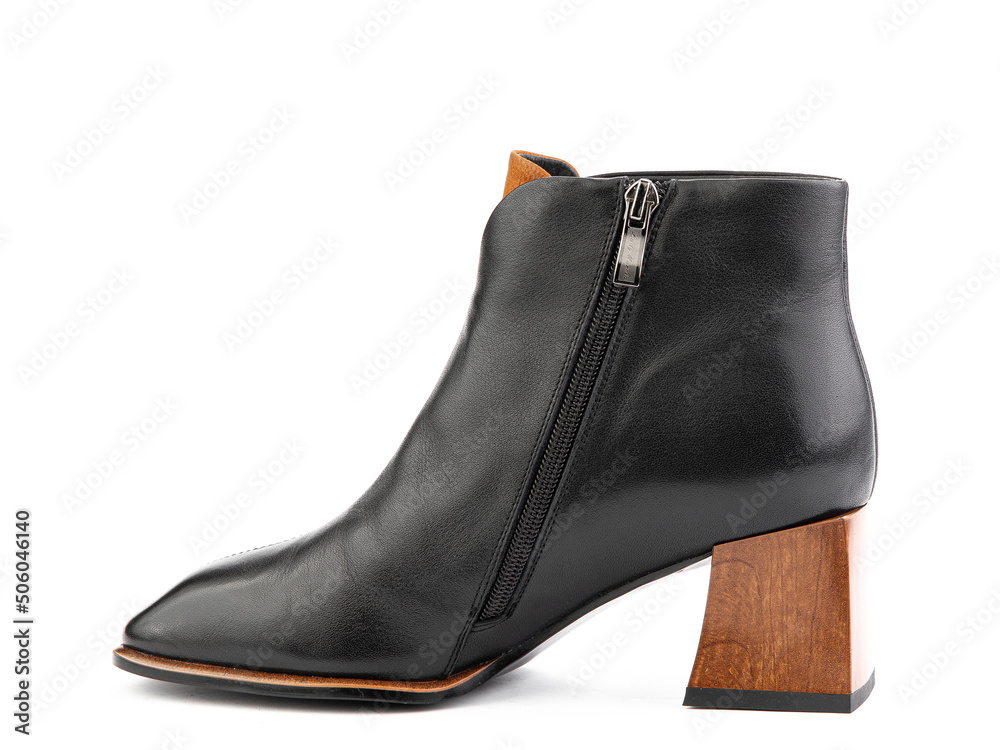Women's autumn ankle black leather boots with black zip and average brown heels, isolated white background. Left side view. Fashion shoes.