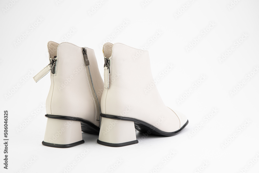 Women's autumn ankle white leather boots with zip and average heels, isolated white background. Back side view. Fashion shoes.