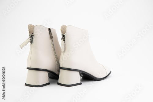 Obraz na płótnie Women's autumn ankle white leather boots with zip and average heels, isolated white background. Back side view. Fashion shoes. w salonie