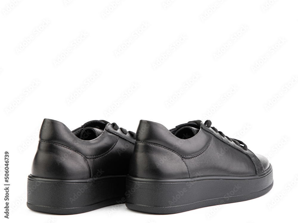 Black leather classic sneakers with laces. Casual women's style. Black rubber soles. Isolated close-up on white background. Back side view.