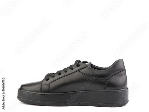 Obraz na płótnie Black leather classic sneakers with laces. Casual women's style. Black rubber soles. Isolated close-up on white background. Left side view. w salonie