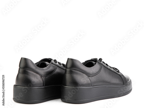 Obraz na płótnie Black leather classic sneakers with laces. Casual women's style. Black rubber soles. Isolated close-up on white background. Back side view. w salonie